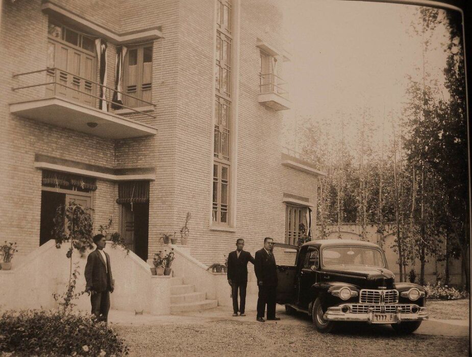 A driver opening the car door for an old Iranian businessman